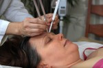 A woman getting her eyebrows cut with tweezers.
