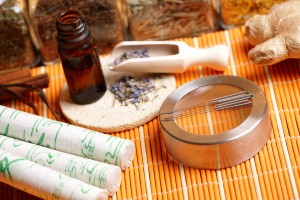 Acupuncture needles, moxa sticks, lavender petals with macerated oil, giner and herbs in jars. TCM Traditional Chinese Medicine concept photo